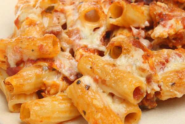 Close-up of baked rigatoni topped with melted cheese, rich tomato sauce, and sprinkled herbs.